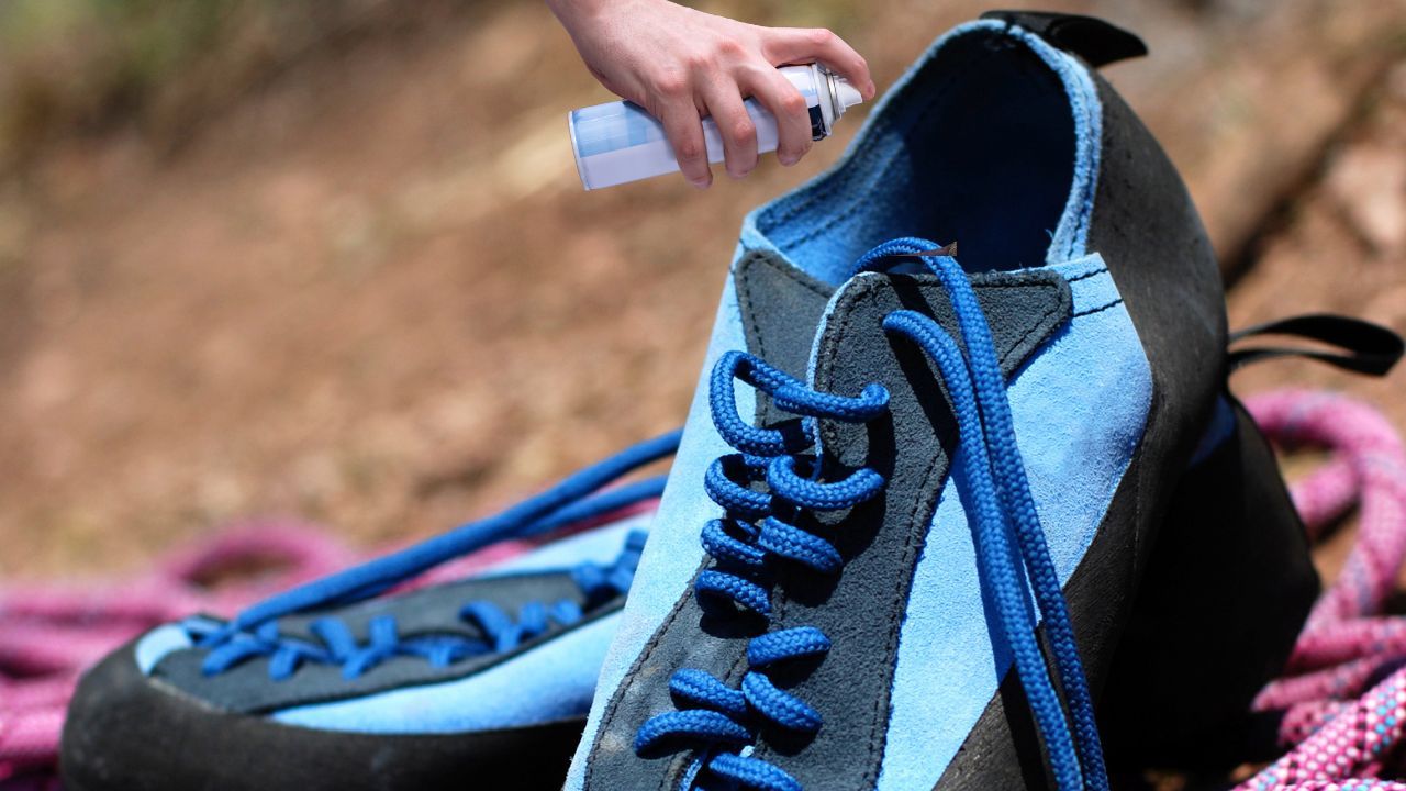 An image of a person using odor-fighting spray on their climbing shoes as a part of how to clean climbing shoes process.
