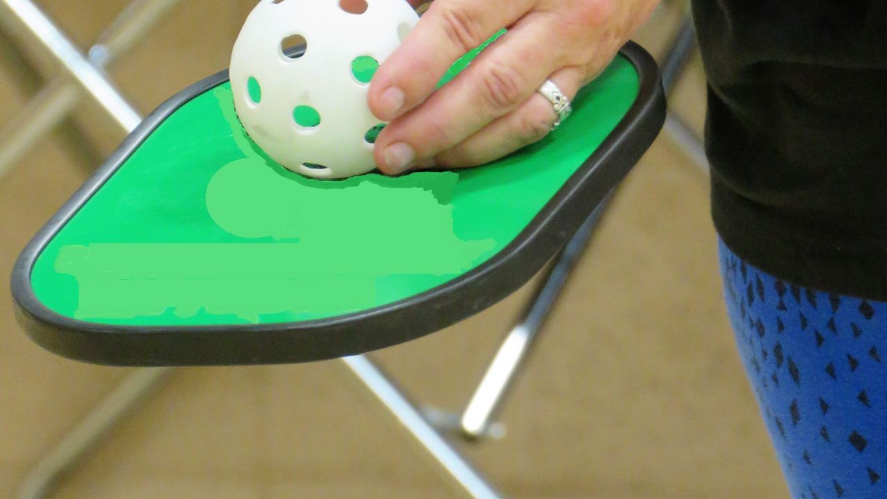 A pickleball paddle with a graphite face and a wooden core