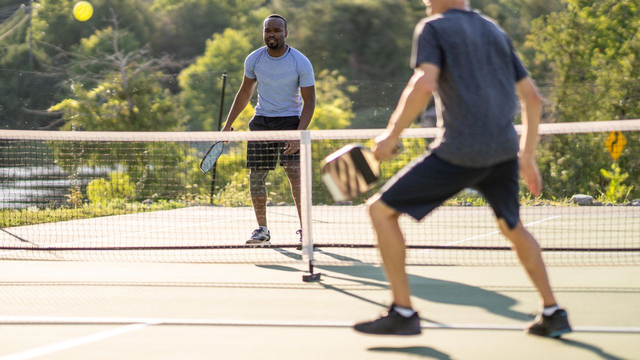 Two players playing pickleball on a court with a net in the middle