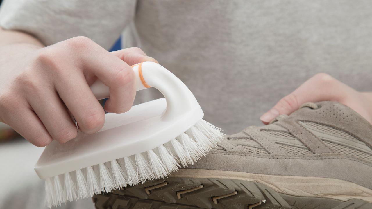 A person restoring the texture of a pair of shoes with a soft bristled brush