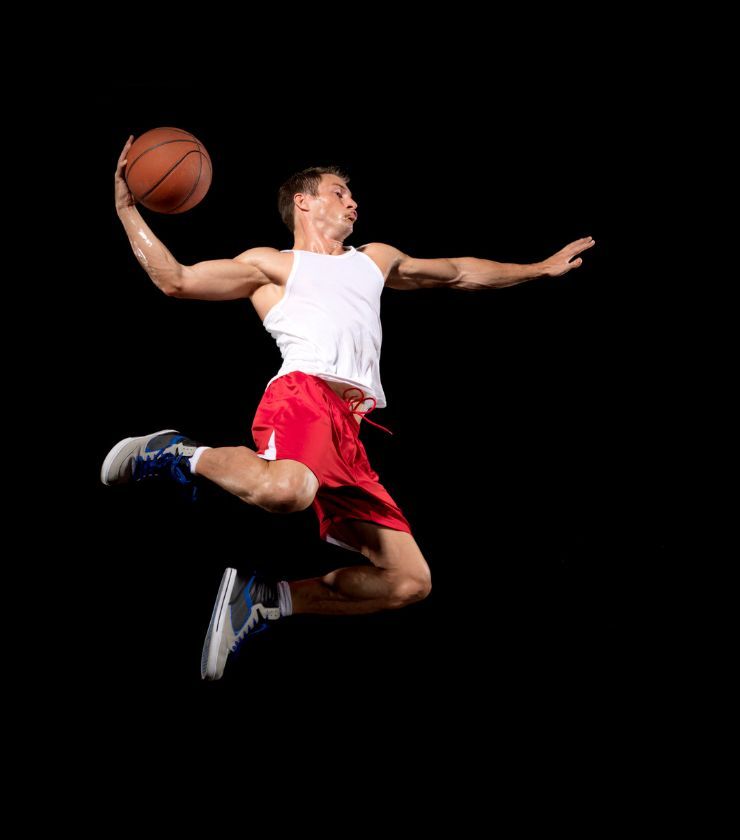 A person doing a vertical jump with a basketball in their hands.