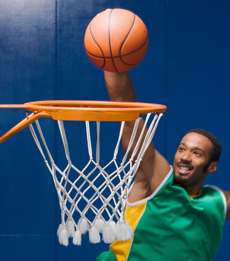 A person dunking a basketball with a big smile on their face.