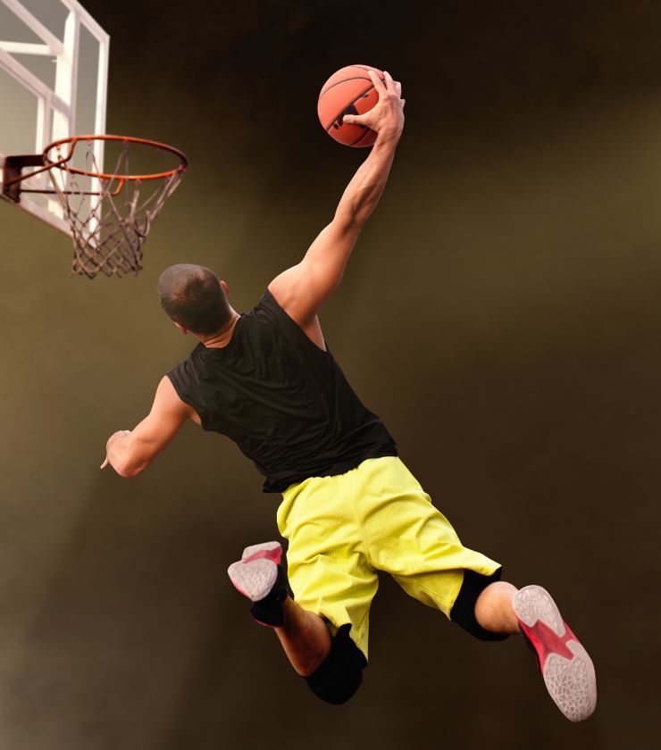 A person jumping high in the air with a basketball in their hands.