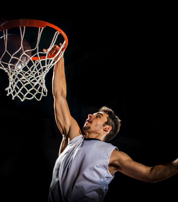 A person jumping high in the air with a basketball in their hands.